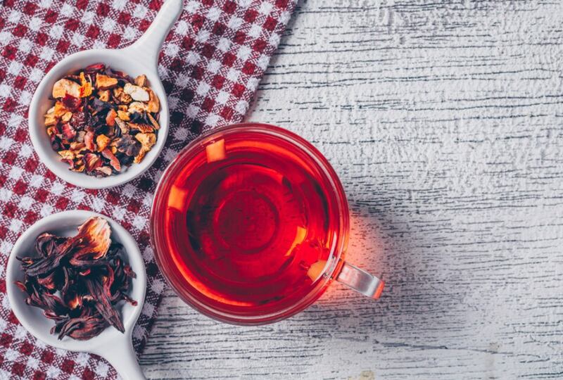 Taza de té con té de hierbas vista superior sobre un paño de picnic y fondo de madera gris